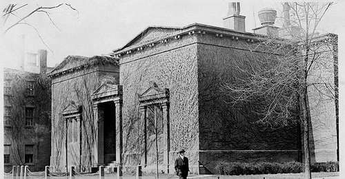 This is a black and white photo of a cryptic building with no windows.