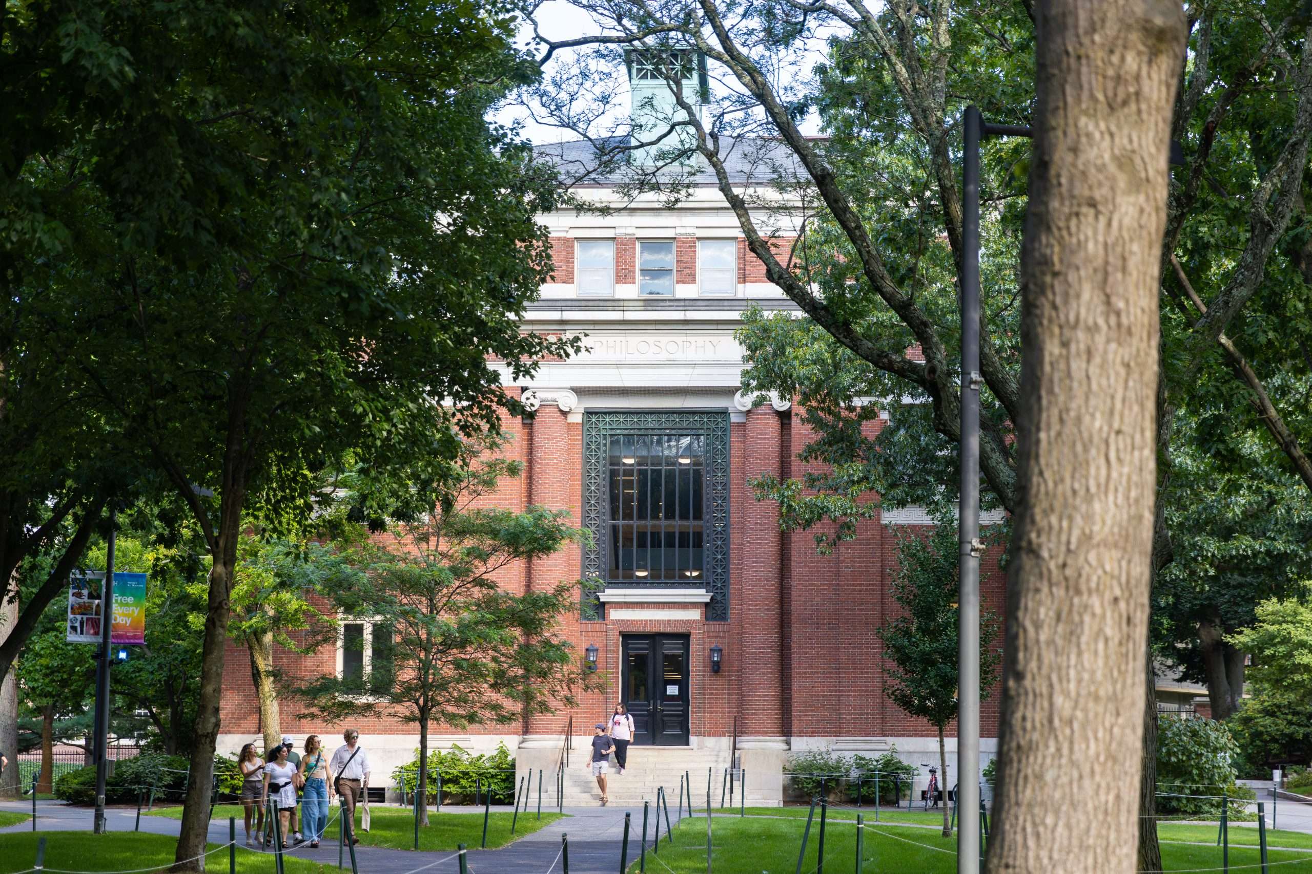 Students walk out of a Harvard University building with the word Philosophy inscribed on top.