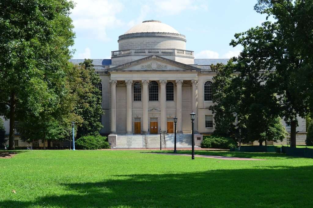 Louis Round Wilson Library is featured beyond a green lawn at the University of North Carolina at Chapel Hill.
